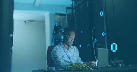 IT professional typing on laptop in server room causing binary digits processing network data - Powered by Adobe