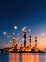  brightly lit industrial refinery at dusk with digital network connections illustrated above, reflecting on calm water.