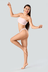 Young woman in underwear with cellulite problem on light background