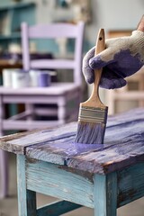 Obraz premium Close-Up of Hand Painting Wood with Purple Paint Over Light Blue Wooden Tabletop
