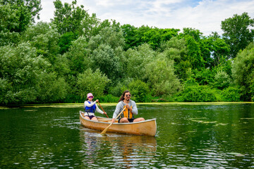 paddling on the toronto islands on a summer day: young adult couple in light brown kevlar canoe...