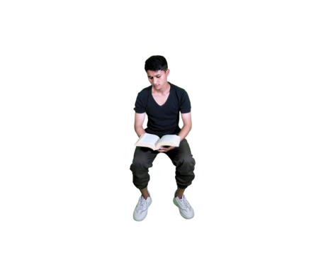 A young man is sitting while reading a book.