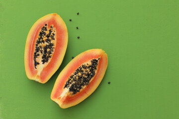 Papaya cut into two pieces, on a green background, fruit, top view