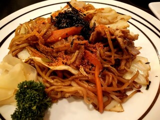 Japanese yakisoba noodles with pork, vegetables and spicy chili powder served on white plate with...