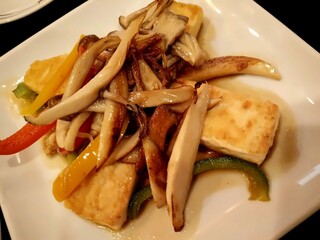 Stir-fried tofu with king oyster mushrooms and bell peppers in light soy sauce served on white plate – healthy Asian vegan dish
