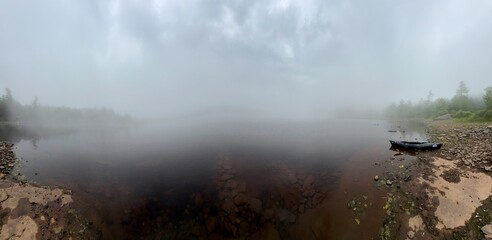 Dense, thick, grey sunrise mist and morning fog rolls in over water at North South Lake in Haines...