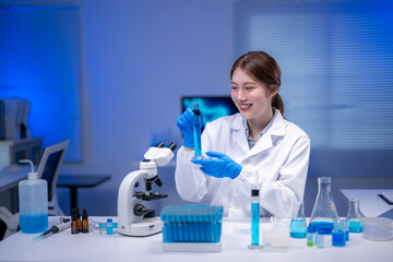 Scientist analyzing blue chemical liquid in laboratory using petri dish and test tube