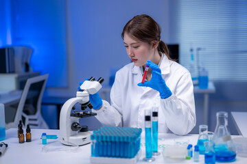 Scientist analyzing blood sample and using microscope in laboratory