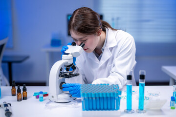 Scientist using microscope analyzing samples in laboratory researching new medicine or vaccine