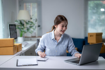 Asian businesswoman calculating and working on laptop in home office