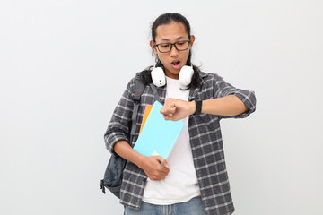 Young asian college student wearing casual clothes, glasses, backpack, holding books, looking at...