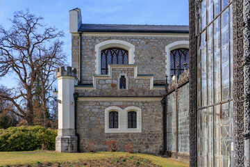 Obraz premium Historic stone building with turret and iron detailing in garden setting