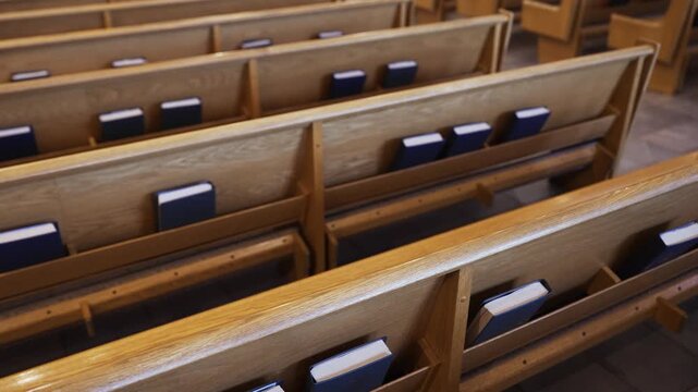 Slow-motion footage of walking behind a church pew that shows blue books of The Holy Bible in a catholic church before mass.
