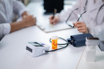 A doctor is writing on a clipboard next to a blood pressure cuff