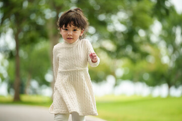 happy toddler girl walk along a pathway in park