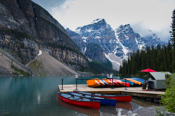 Exploring Moraine Lake Banff with colorful canoes on the dock and majestic mountain backdrop on a...