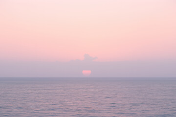 Soft pink sunset over calm ocean water with gentle waves and peaceful atmosphere