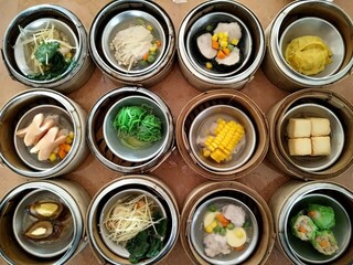 Thai local dim sum set in bamboo baskets – colorful southern-style fusion breakfast served in...