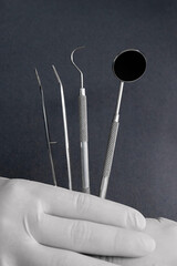 Close-up of gloved hands holding stainless steel dental instruments &mdash; mirror and probe. Concept of hygiene, dental care, and professional dentistry tools.

