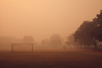 Obraz premium Foggy Soccer Field Under Hazy Sky at Dusk in Urban Environment