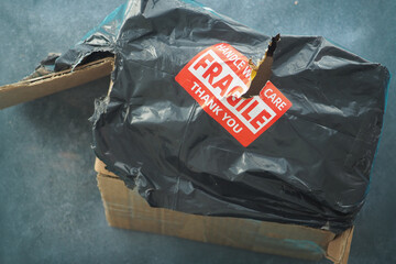Damaged package with fragile label on blue background