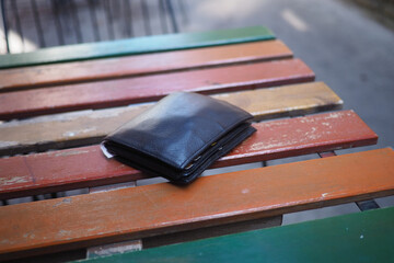 Black wallet resting on colorful wooden table outside, lost wallet concept 