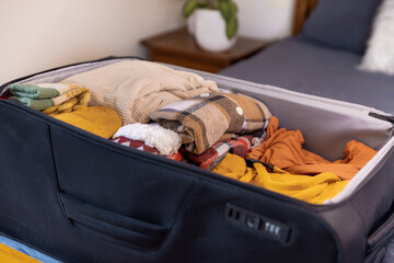 Open suitcase full of warm clothes ready for winter vacation