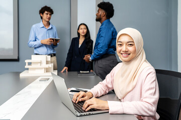 Portrait of smiling Muslim women working on a laptop, With a background as male and female...