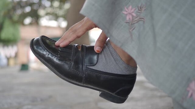 Woman adjusts her shoe while walking in the city