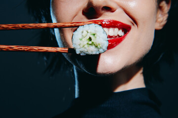 Woman with red lips enjoying sushi with chopsticks, showcasing elegance and delicious flavors in a...