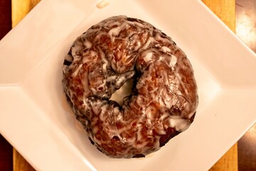 Large doughnut served as a cake on a white plate with a vanilla glaze