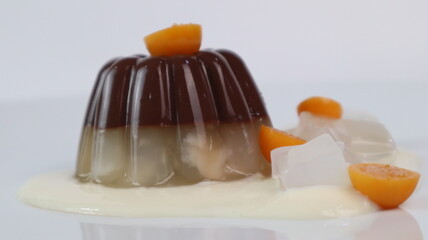 chocolate coconut pudding on a white plate with small orange fruit topping