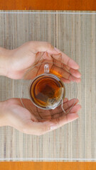 Top view of hands holding cup of tea with teabag isolated on wooden background