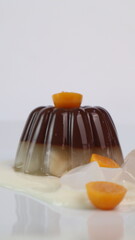 chocolate coconut pudding on a white plate with small orange fruit topping
