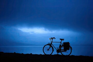 Obraz premium Silhouette of bicycle by lake at twilight
