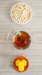 Top view of a cup of tea with teabag inside, sugar cubes, and snacks isolated on wooden texture...