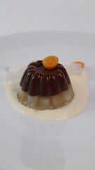 chocolate coconut pudding on a white plate with small orange fruit topping