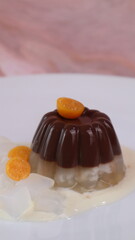 chocolate coconut pudding on a white plate with small orange fruit topping