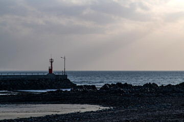 beacon on the beach at the cloudy sea