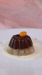 chocolate coconut pudding on a white plate with small orange fruit topping