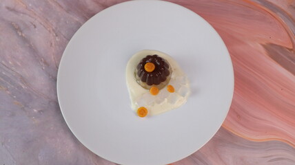 chocolate coconut pudding on a white plate with small orange fruit topping