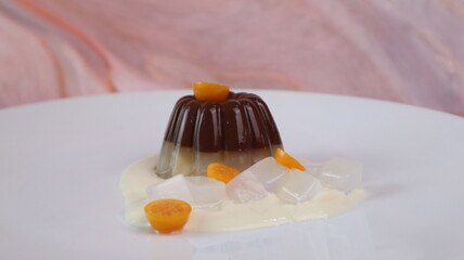chocolate coconut pudding on a white plate with small orange fruit topping