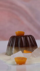 chocolate coconut pudding on a white plate with small orange fruit topping