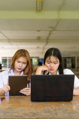 Young Thai University Students Relaxing Together at Campus Cafe Outdoors Using Technology