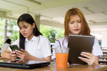 Young Thai University Students Relaxing Together at Campus Cafe Outdoors Using Technology