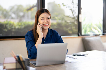 Smiling female entrepreneur discussing over mobile phone while at home office .Female business...