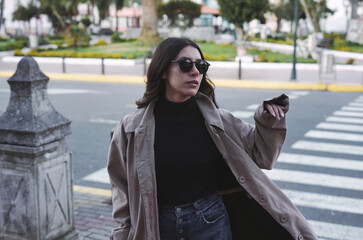 Stylish woman hailing a taxi on city street