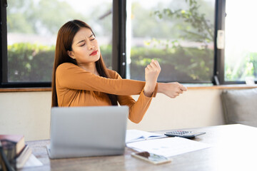 Office asian business woman stretching body for relaxing while working with laptop computer at her...