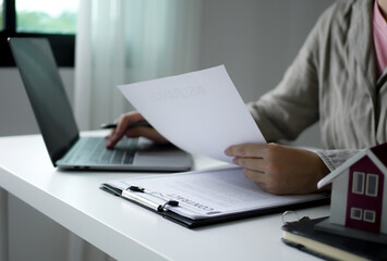 A young woman real estate service worker is sitting at a computer searching for information and arranging house rentals for clients with care and professionalism