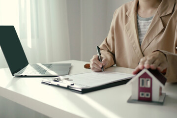 A young woman real estate service worker is sitting at a computer searching for information and arranging house rentals for clients with care and professionalism